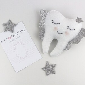 May include: A white felt tooth with silver glitter wings and a crown, with a pink heart and the text "MY TOOTH CHART" on a white card with a tooth chart.
