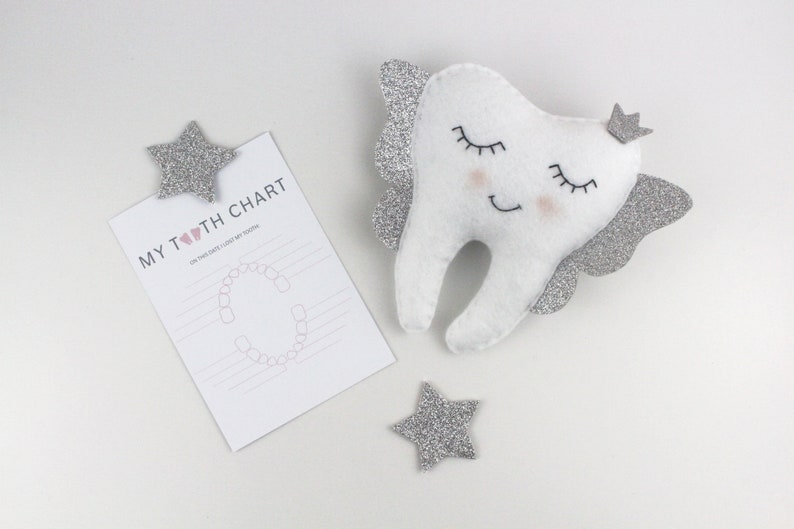 May include: A white felt tooth with silver glitter wings and a crown, with a pink heart and the text "MY TOOTH CHART" on a white card with a tooth chart.