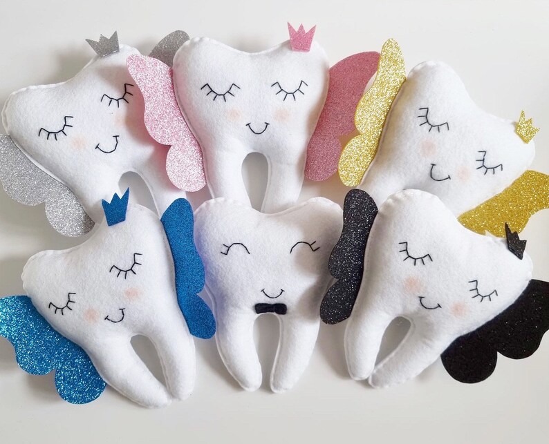 May include: A set of ten plush tooth-shaped toys with different colored glitter accents. Each tooth has a different facial expression and a crown on top.