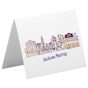Puede incluir: Una tarjeta blanca con una ilustración morada y dorada de los edificios del campus de la LSU y el estadio Tiger de la LSU. El texto "Jackson Murray" está impreso en morado debajo de la ilustración.