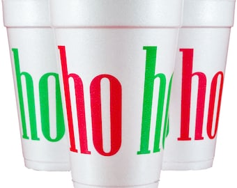 Puede incluir: Tres vasos de espuma blanca dispuestos en grupo. Cada vaso presenta el texto hoho ho impreso en letras rojas y verdes alternadas. Los vasos tienen una superficie texturizada y una forma cilíndrica cónica con un borde ancho y una base estrecha.