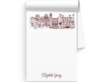Könnte beinhalten: Ein weißer Notizblock mit einer rotbraunen Zeichnung einer Skyline und dem Text "Elizabeth Young" am unteren Rand.