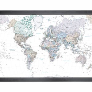May include: A framed world map with a detailed, colourful design. The map features countries, cities, and oceans in various shades of blue, green, brown, and grey. The frame is a dark grey colour, providing a clean, modern look.