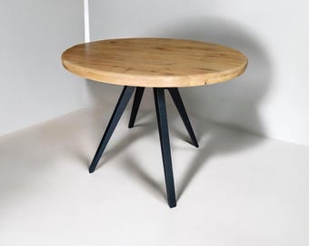 May include: A round wooden table with a light brown finish. The table has three black metal legs. The table is set against a white background.