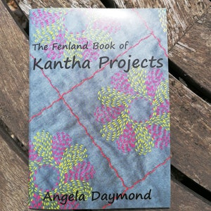 May include: The Fenland Book of Kantha Projects by Angela Daymond. The cover features a blue background with a patchwork design and colorful embroidery.