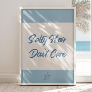 May include: A white framed poster with a light blue and beige background. The poster says "Salty Hair Don't Care" in blue cursive text. A small blue starfish is at the bottom of the poster.