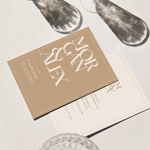 Könnte beinhalten: Eine beigefarbene Hochzeitseinladung mit weißem Text, der "Morgan & Alex" und "July 6th, 2026" lautet, mit dem Text "Invite you to celebrate their love and marriage" darunter. Eine kleinere weiße Karte mit dem Text "M & A" in der oberen rechten Ecke und dem Text "July 6th, 2026" und "The Afternoon" darunter.