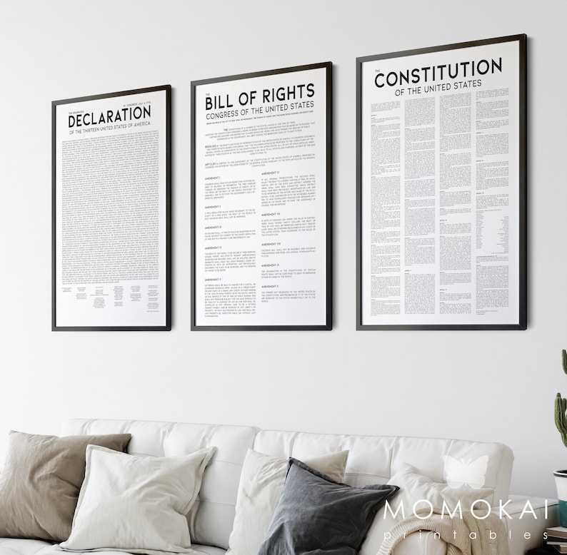 May include: Three framed prints of historical documents hang on a white wall. The prints include the Declaration of Independence, the Bill of Rights, and the Constitution of the United States. Each document is printed in black text on a white background.