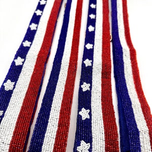 May include: Four beaded straps in red, white, and blue with a star pattern. The straps are made of small beads and have a gold clasp.