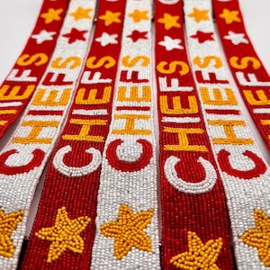 May include: A set of red, white, and yellow beaded keychains with the word "CHIEFS" spelled out in yellow beads. Each keychain features a yellow star.