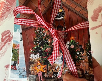 May include: A stack of Christmas cards tied with a red and white gingham ribbon. The cards feature illustrations of a barn scene with a Christmas tree, animals, and people.