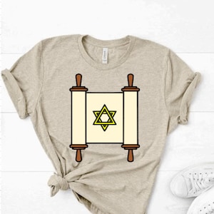 May include: A beige t-shirt with a graphic of a scroll with a yellow Star of David on it.
