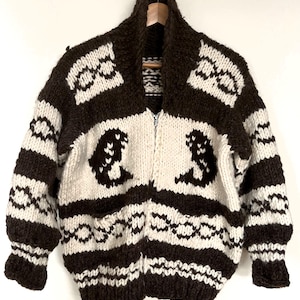 May include: A brown and white striped knitted cardigan with a zipper closure. The cardigan features a geometric pattern and two pockets.