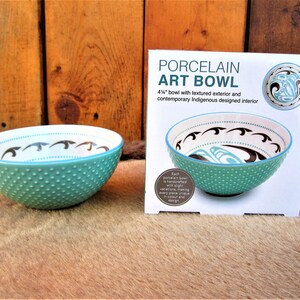 May include: A turquoise porcelain art bowl with a textured exterior and a contemporary Indigenous design on the interior. The bowl is 4 1/2 inches in diameter. Each bowl is handcrafted with slight variations, making every piece unique in colour and design.