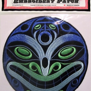 Può includere: Toppa ricamata con un designo stilizzato di un viso blu, verde e bianco. La toppa è rotonda e ha uno sfondo nero. Il testo "Golden Top Embroidery Patch" è stampato sulla confezione.