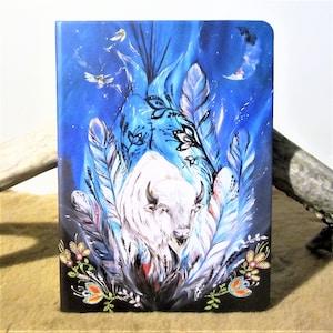 Peut inclure: Un buffle blanc se tient dans un champ de plumes bleues et blanches, avec une lune croissante et des étoiles en arrière-plan. Le buffle est entouré de fleurs et de papillons.