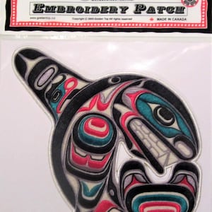 Può includere: Toppa ricamata con un designo di orca stilizzato e colorato. La toppa è nera, bianca, rossa, blu e verde. Il testo "Golden Top" e "Embroidery Patch" è visibile sulla confezione.