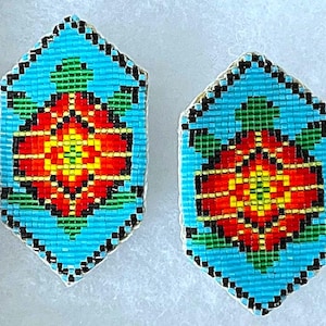 Könnte beinhalten: Ein Paar sechseckige Perlenohrringe mit türkisfarbenem Hintergrund und einem roten, gelben und grünen Blumendesign.