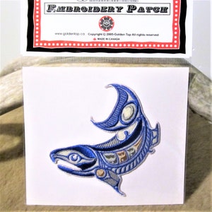May include: Blue and white embroidered patch of a stylised salmon with a crescent moon shape on its back. The patch is on a white background and has the text "EMBROIDERY PATCH" at the top.