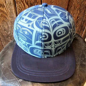 May include: A blue baseball cap with a flat brim. The cap features a repeating pattern in a lighter shade of blue, with a button on top. The brim is a solid dark blue color.