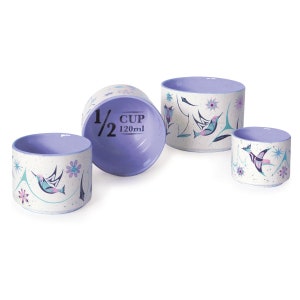 Peut inclure: Ensemble de quatre tasses à mesurer en céramique blanche et violette avec un motif de colibri. Les tasses sont étiquetées avec des mesures en tasses et en millilitres. 1/2 tasse, 1/4 tasse, 1/8 tasse et 1/16 tasse.