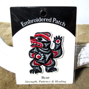 Può includere: Toppa ricamata con un orso stilizzato nero e rosso con il testo "Embroidered Patch" e "Bear Strength, Patience & Healing".