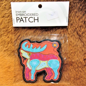 Può includere: Toppa ricamata da stirare con un design di alce colorato. L'alce è contornato di nero e ha una combinazione di colori rosso, blu e giallo. La toppa è confezionata in una busta di plastica trasparente con un'etichetta bianca che recita "toppa ricamata da stirare".