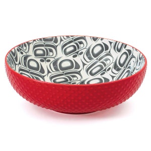 Può includere: Una ciotola in ceramica rossa con un esterno testurizzato e un interno bianco con un motivo geometrico nero e grigio.