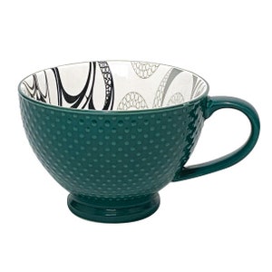 May include: A green ceramic mug with a white interior and a black and gray abstract design. The mug has a textured exterior with small raised dots.