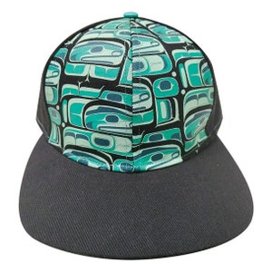May include: A black and green patterned baseball cap with a black brim. The pattern features a repeating design of stylised figures.