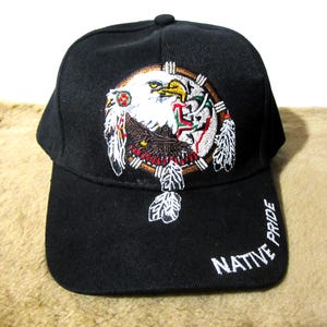 May include: Black baseball cap with an embroidered design of a Native American eagle inside a dreamcatcher with feathers. The text "NATIVE PRIDE" is embroidered on the side of the cap.