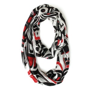 Peut inclure: Une écharpe infinie noire, blanche et rouge avec un motif géométrique. Le motif rappelle l'art amérindien.