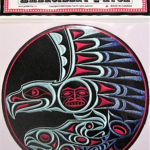 Può includere: Una toppa rotonda nera ricamata con un design stilizzato di un uccello con le ali spiegate e un pesce nelle sue grinfie. L'uccello e il pesce sono contornati da filo rosso e blu, su uno sfondo nero. La toppa è etichettata "Golden Top Embroidery Patch" e "Made in Canada".