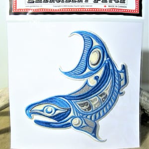May include: Blue and white embroidered patch depicting a stylised salmon with a crescent moon design. The patch is on a white background and features the text "EMBROIDERY PATCH" at the top.