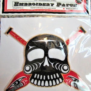 May include: Black and white embroidered skull with red and white paddles crossed behind it. The skull has a gold outline and the paddles have a gold tip. The patch is packaged in a clear plastic bag with a white backing card that says "Golden Top Embroidery Patch" and "Made in Canada".