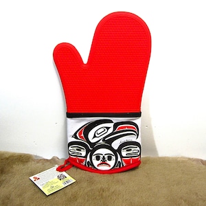 Può includere: Guanto da forno in silicone rosso con un design bianco e nero che presenta un'aquila stilizzata e altre arti native. Il guanto ha un anello per appenderlo.