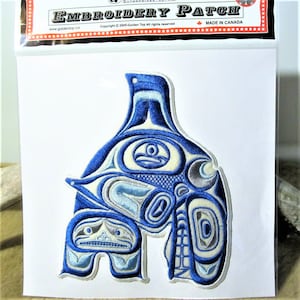Könnte beinhalten: Blau-weißer gestickter Aufnäher mit einem stilisierten Design eines Wals und einer kleineren Kreatur. Der Aufnäher ist in Kanada hergestellt und trägt den Text "Embroidery Patch" und "Made in Canada".