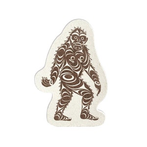 May include: A brown and white sticker with a stylized illustration of a Sasquatch or Bigfoot. The creature is depicted with a detailed pattern of circles and lines.