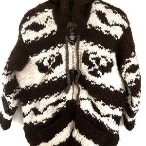 May include: A brown and white striped hooded sweater with a zipper closure. The sweater has a geometric pattern and two pockets.