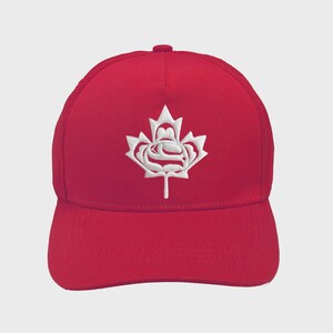 May include: A red baseball cap featuring a white embroidered maple leaf emblem. The cap has a curved peak and a rounded crown. The maple leaf design is centrally placed on the front.