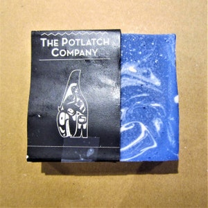 Può includere: Un sapone blu e bianco marmorizzato con un'etichetta bianca che recita "The Potlatch Company".