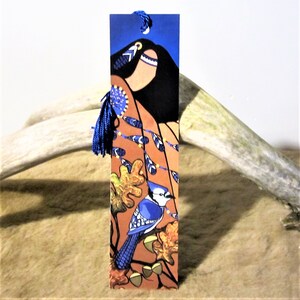 May include: Blue jay bookmark with a blue tassel. The bookmark features a stylised Native American woman with a blue and yellow patterned dress and a blue jay perched on a branch with autumn leaves.