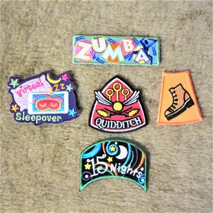 May include: Five colourful embroidered patches with various themes. The patches include "Zumba", "Virtual Sleepover", "Quidditch", "15 Nights", and a boot.