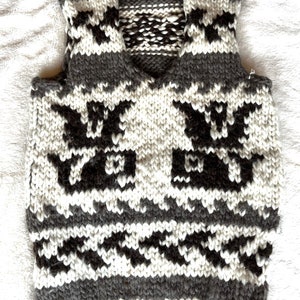 May include: A gray and white knitted vest with a geometric pattern. The vest has a V-neck and sleeveless design.