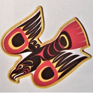 May include: A black, red, and yellow stylized eagle design with a yellow outline. The eagle is in flight with its wings spread. The design is reminiscent of Native American art.