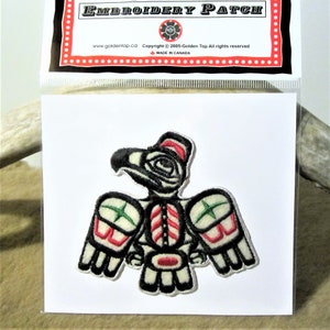 Può includere: Toppa ricamata con un designo di aquila stilizzato in nero, bianco, rosso e verde. La toppa è su uno sfondo bianco e ha il testo "Embroidery Patch" in alto.