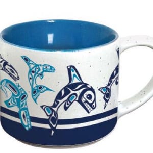 May include: White ceramic mug with a blue interior and a design of stylized orcas and other sea creatures in blue and turquoise. The design is on a white background with a blue stripe at the bottom.