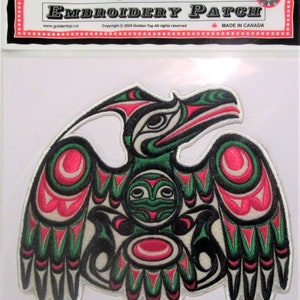 Può includere: Una toppa ricamata con un uccello stilizzato verde, rosso e nero su sfondo bianco. L'uccello ha un becco grande e le ali spiegate. La toppa è realizzata in Canada.