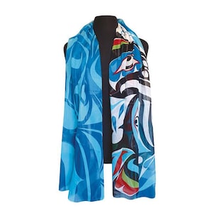 May include: A long, rectangular scarf with a vibrant design. The scarf features a mix of blue hues with abstract patterns on one side and a detailed, colourful design on the other. The scarf is draped over a black mannequin.
