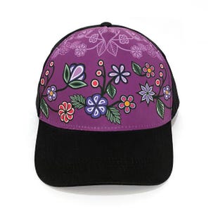 May include: A purple trucker hat with a floral design. The hat has a black mesh back and a black brim.